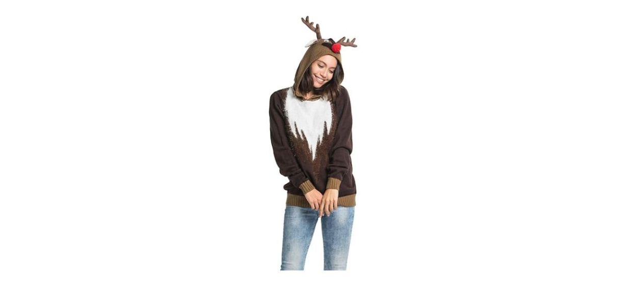 a woman wearing a brown and white hoodie that has reindeer antlers, eyes and a red nose on the hood